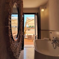 Un baño con una bañera grande, una pared de piedra y vistas al exterior.