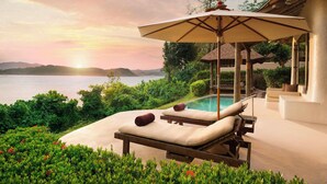 A serene poolside area with lounge chairs and an umbrella, overlooking a body of water and lush greenery. - The Naka Island, a Luxury Collection Resort & Spa, Phuket (Pa Klok)