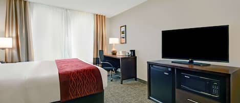 A hotel room with a bed, a desk, a television, and a microwave.