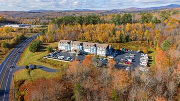 A large hotel with multiple buildings, a parking lot, and a road curving around the property.