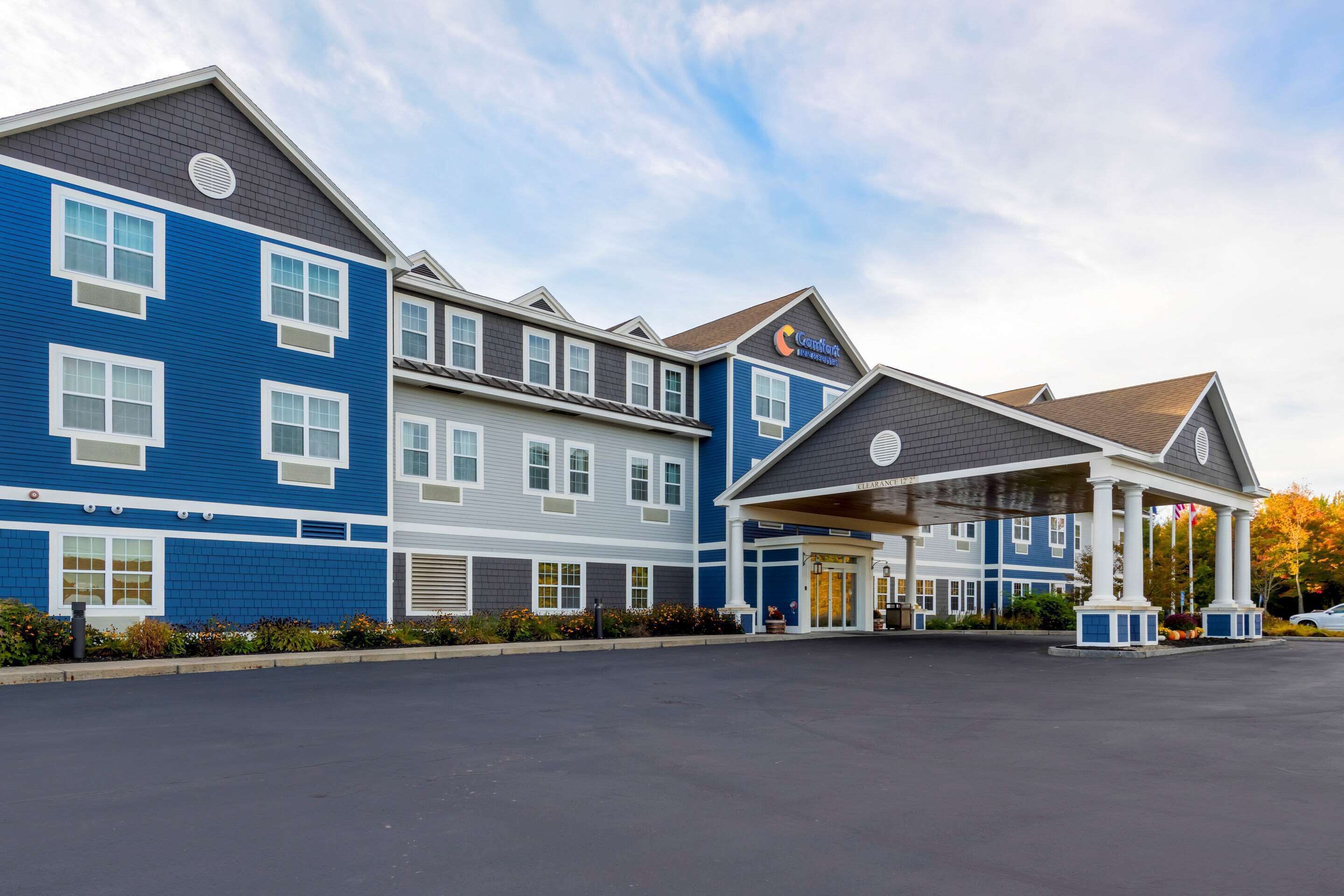 A hotel with a blue facade, a covered entrance, and a parking lot.