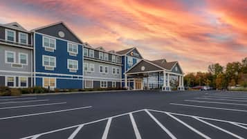 A hotel with a parking lot and a building with multiple windows and a sign.