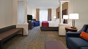 A hotel room with a large bed, a sofa, a bench, and a desk with a lamp. - Comfort Inn & Suites Wilton (Wilton)