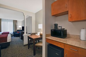 Habitación de hotel con dos camas, un escritorio, una silla, un microondas y un refrigerador.