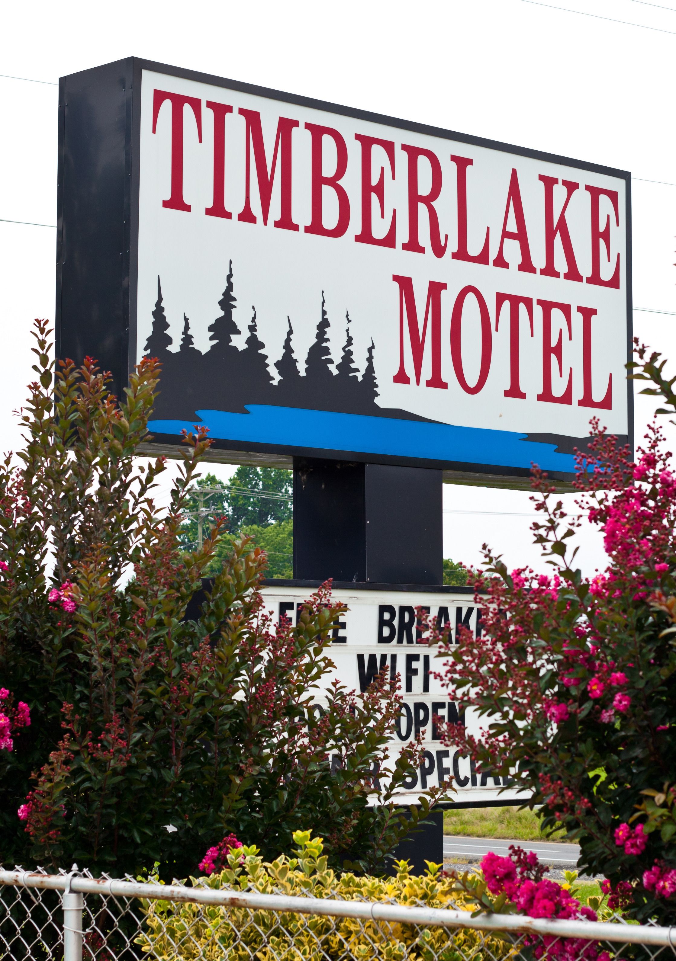 A sign for Timberlake Motel with a silhouette of trees and a blue sky.