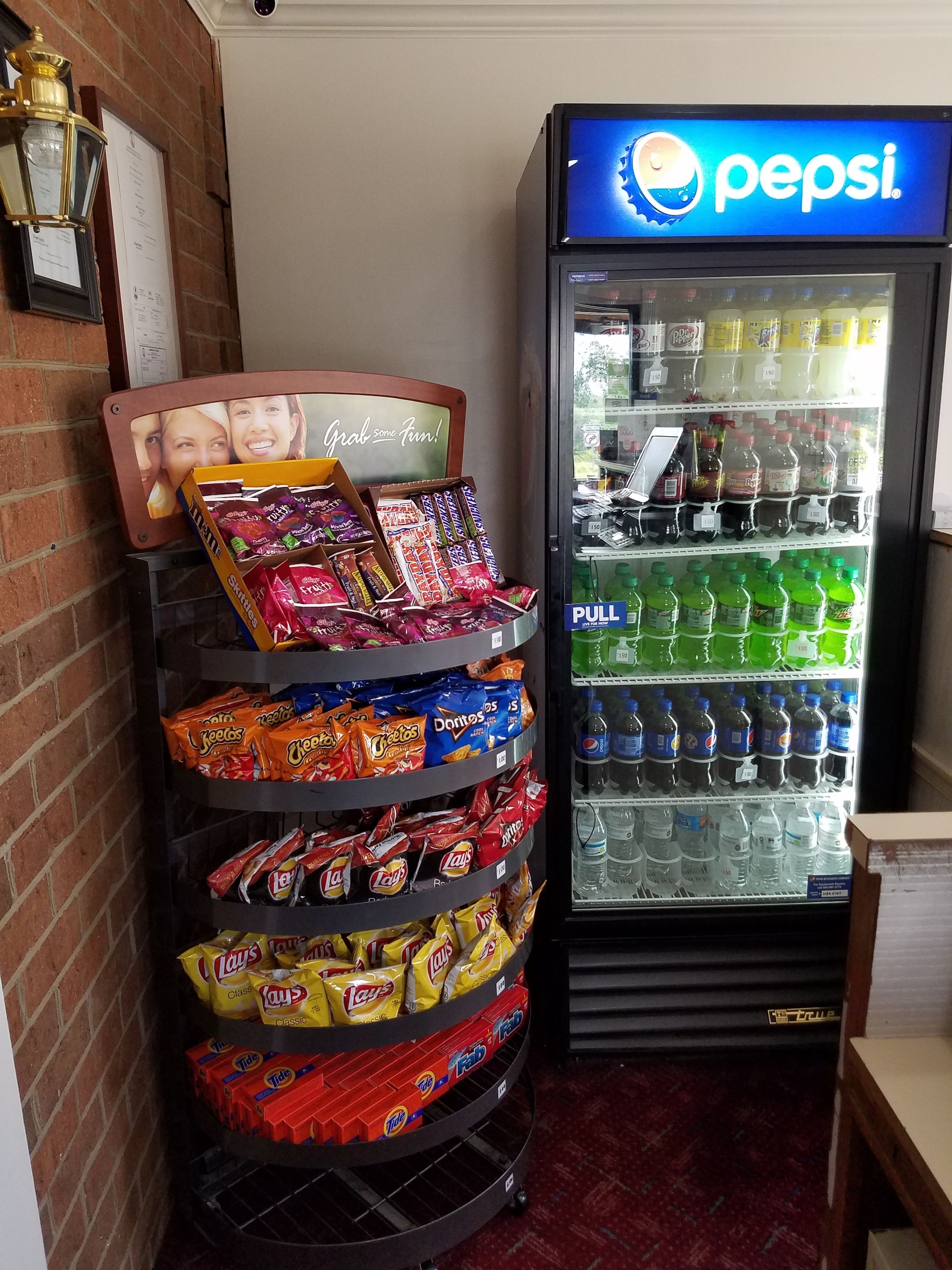 A vending machine stocked with snacks and a Pepsi refrigerator.