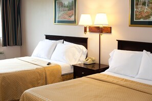 A hotel room with two beds, a nightstand with a lamp, and a painting on the wall.