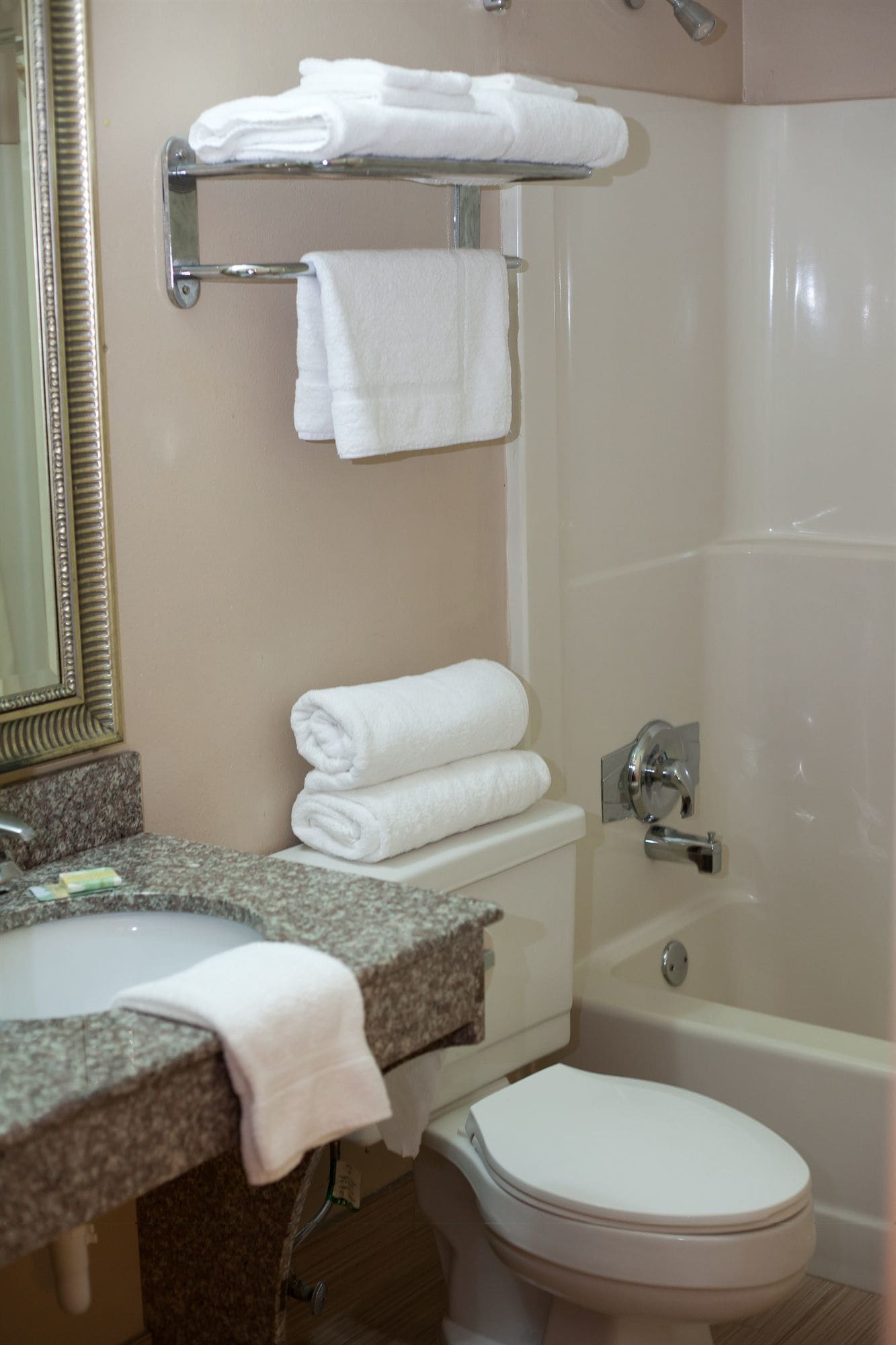 A bathroom with a sink, mirror, towel rack, toilet, and bathtub.