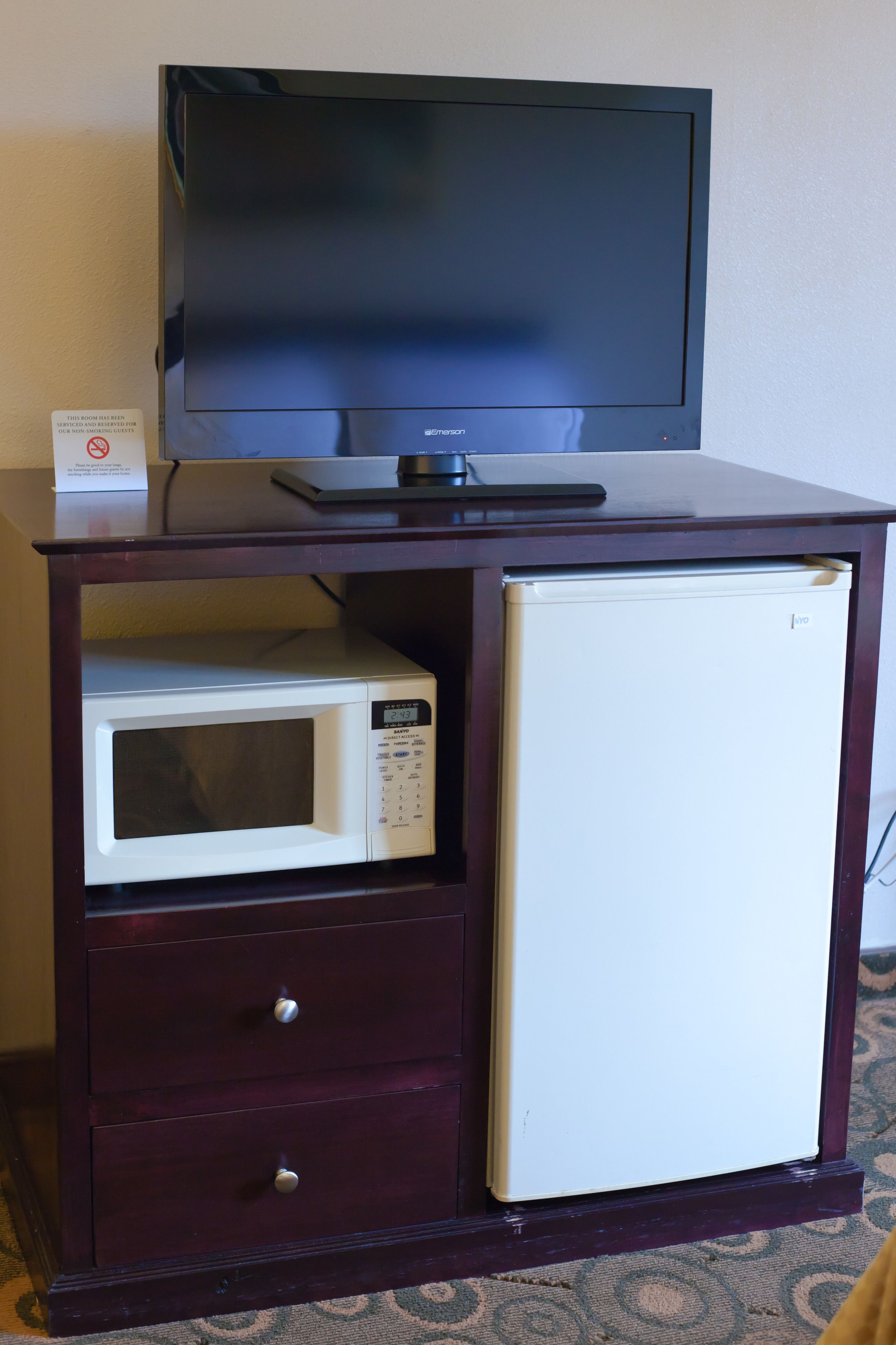 A compact minibar with a microwave and a small refrigerator.