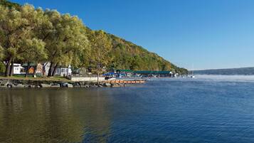 A lakeside property with a dock, boats, and a building with a green roof.