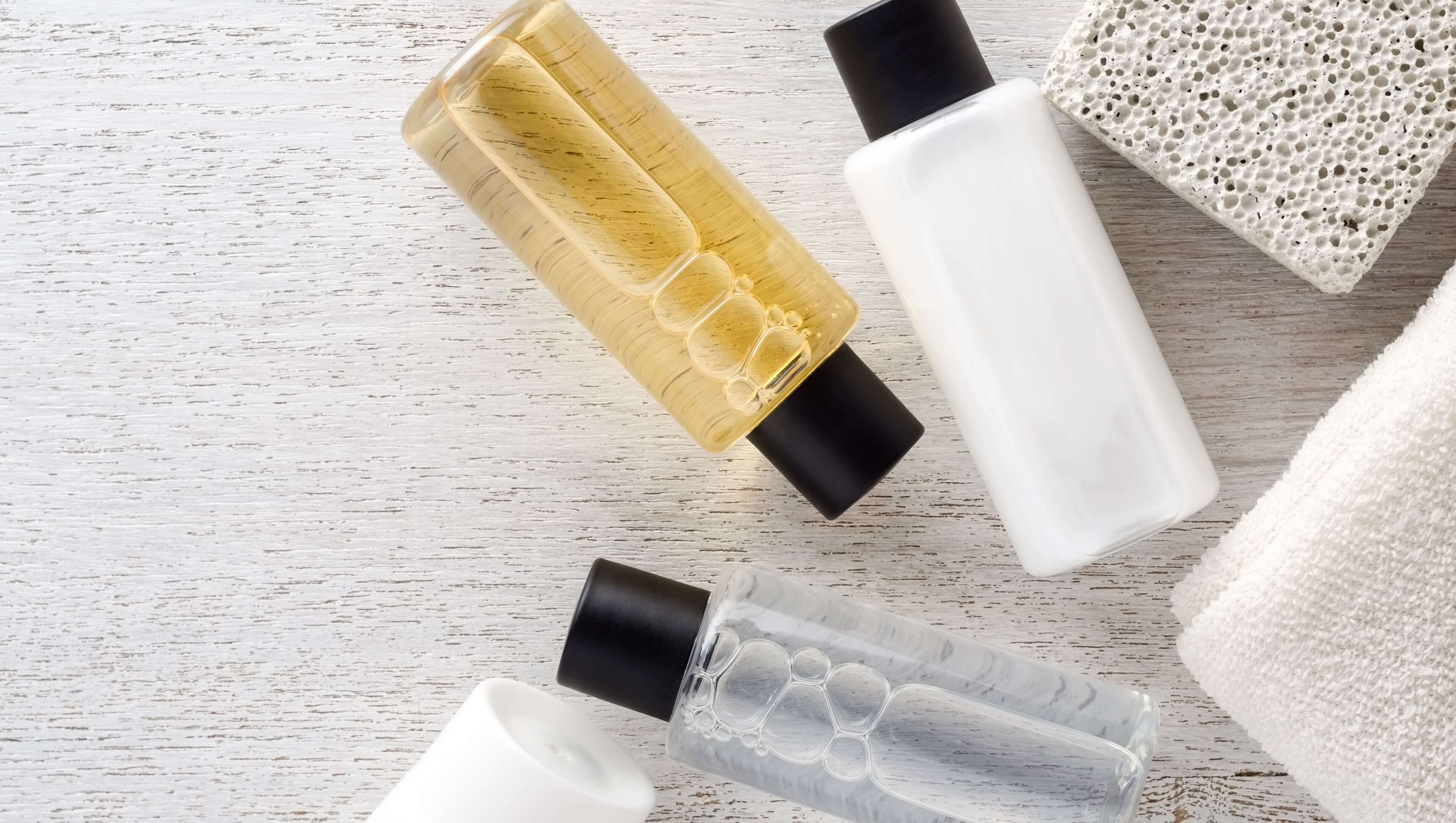 Tres frascos de productos para el cuidado de la piel sobre una superficie de madera.