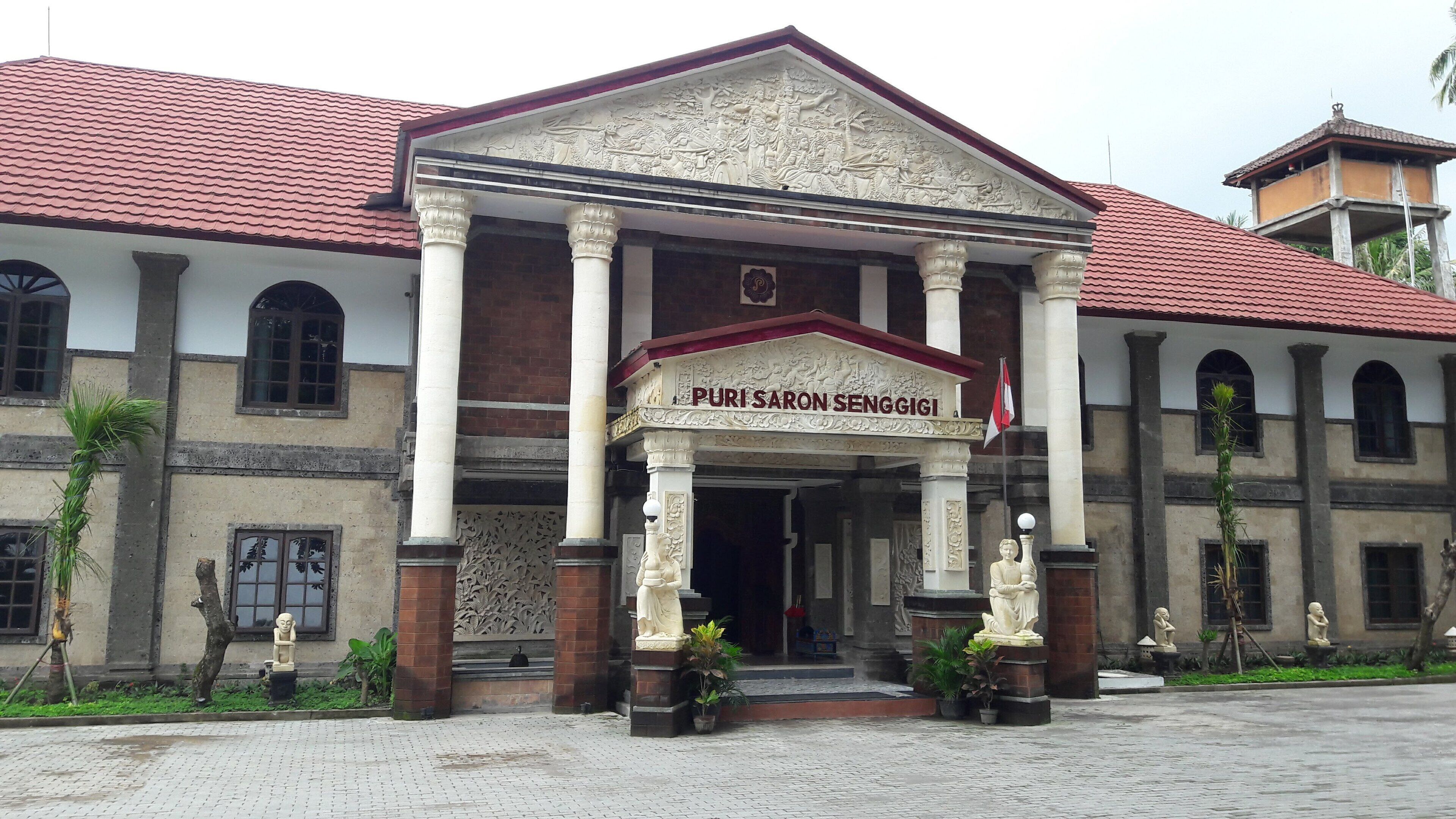 A building with a sign reading "Puri Sarong Senggigi" and a traditional architectural style with columns and a tiled roof.