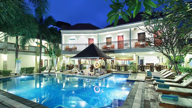 A swimming pool with lounge chairs and a bar area, surrounded by a two-story building with balconies. - The Niche Bali (Kuta)