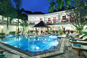 A swimming pool with lounge chairs and a bar area, surrounded by a two-story building with balconies. - The Niche Bali (Kuta)