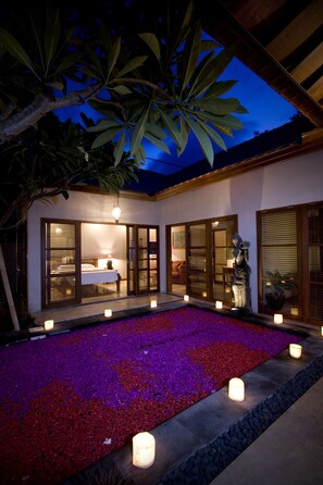 A courtyard with a bed, a statue, and a water feature with candles. - Ajanta Villas (Denpasar)