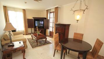 Una sala de estar con sofá, mesa de centro, televisor y mesa de comedor con sillas.