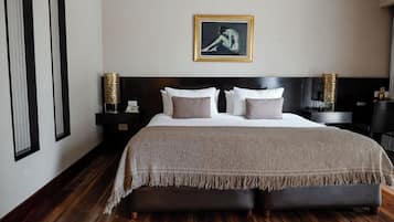 A bedroom with a large bed, a headboard, bedside tables, and a framed artwork on the wall.