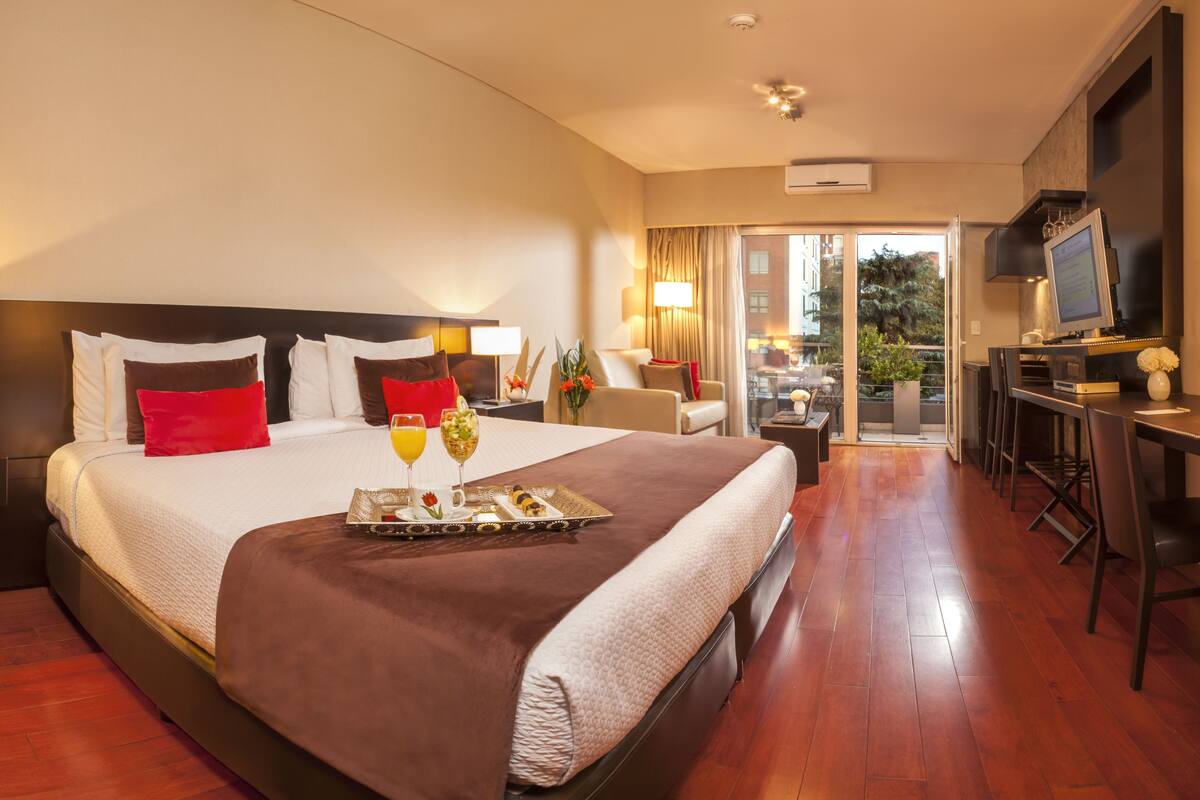 Une chambre d’hôtel avec un grand lit, un bureau et un balcon offrant une vue.
