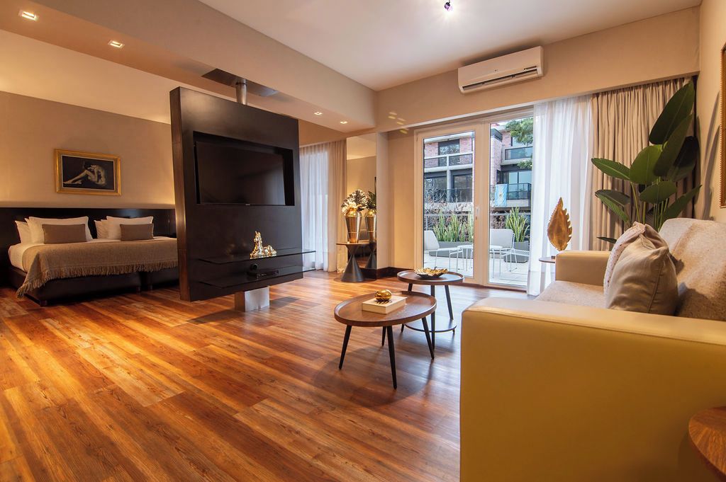 Una sala moderna con cama, televisor de pantalla plana, sofá y comedor.