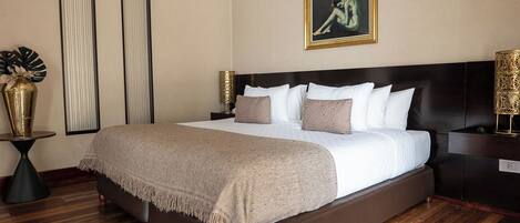 A neatly made bed with a dark headboard, two bedside tables with lamps, and a framed artwork on the wall.