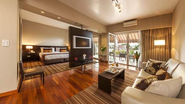 Ein Hotelzimmer mit einem Bett, einem Fernseher, einem Sofa und einem Esstisch.