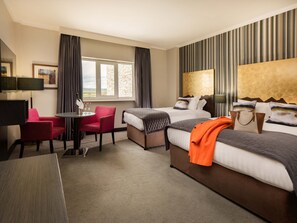 Habitación de hotel con dos camas, un escritorio, una silla y una ventana con cortinas.