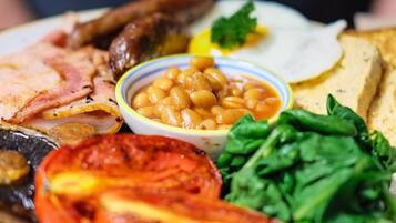 Une assiette de nourriture contenant divers aliments, notamment des haricots, des tomates et des légumes verts.