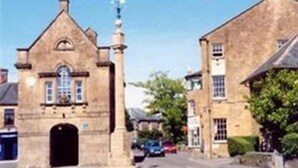 A stone building with a prominent entrance and a small tower-like structure on top. - White Hart Hotel (Martock)
