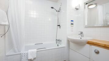 A modern bathroom with a white tiled shower, a sink with a wooden countertop, and a mirror above the sink.
