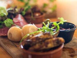 Una tabla de madera con distintos alimentos, como champiñones, cebollas y hierbas aromáticas.