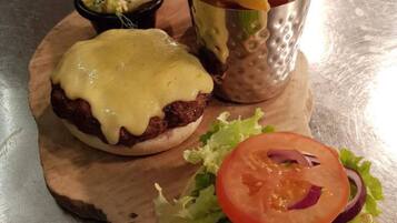Una comida con una hamburguesa cubierta de queso, un sándwich de lechuga y tomate, y una porción de papas fritas.
