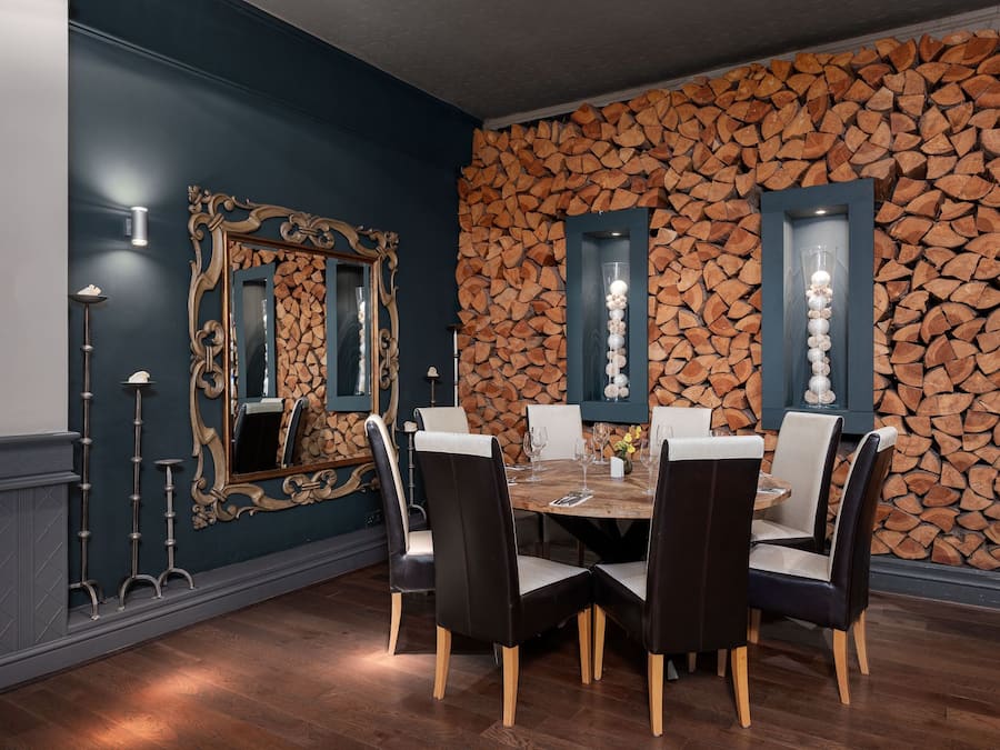 A dining room with a round table, six chairs, and a decorative mirror.