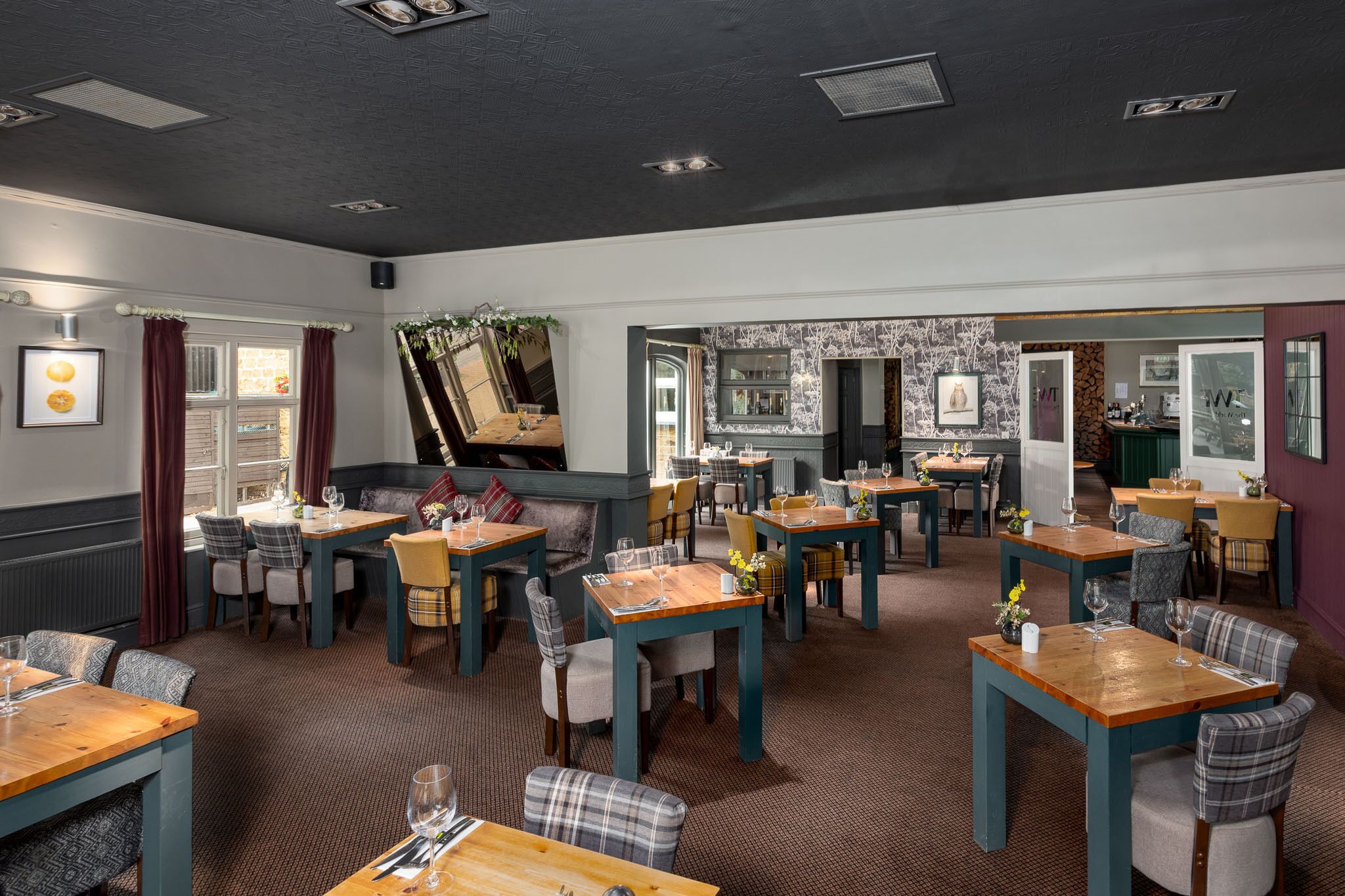 A restaurant with multiple tables and chairs, a bar area, and a view of the kitchen.