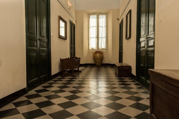 A hallway with a checkered floor, wooden doors, and a large vase in the center. - Hotel Florenz (Finale Ligure)