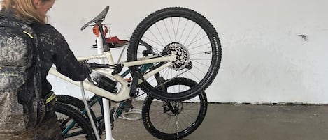 A person working on a bicycle in a garage with a concrete floor and white walls.