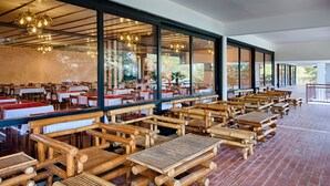 A restaurant with bamboo furniture, large windows, and a brick floor. - Hotel Issa (Vis)