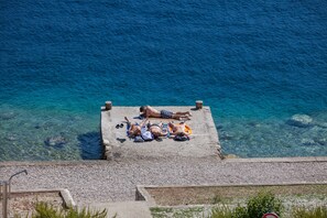 A concrete platform with people sunbathing by the sea.