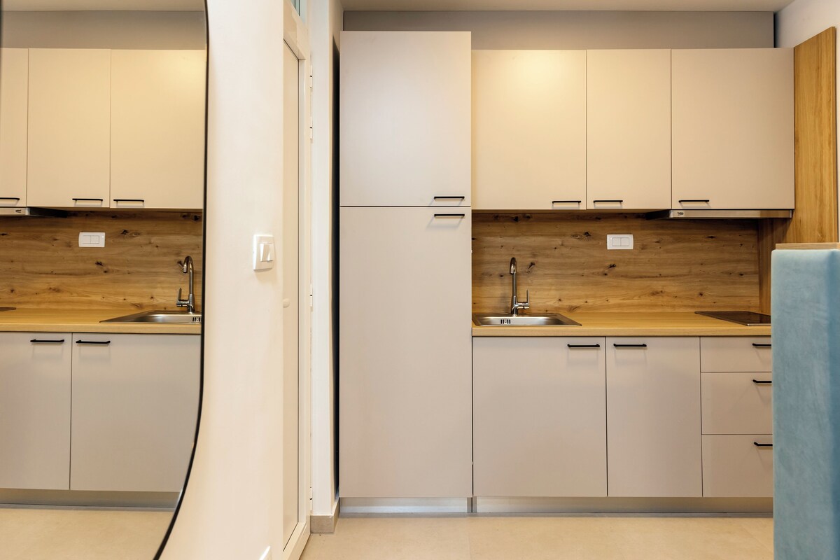 A modern kitchen with white cabinets, wooden countertops, and stainless steel appliances.