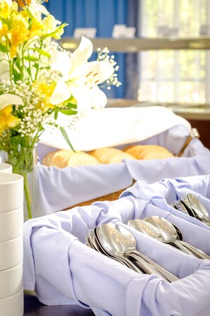 A table set with white napkins, silverware, and a bouquet of yellow flowers.