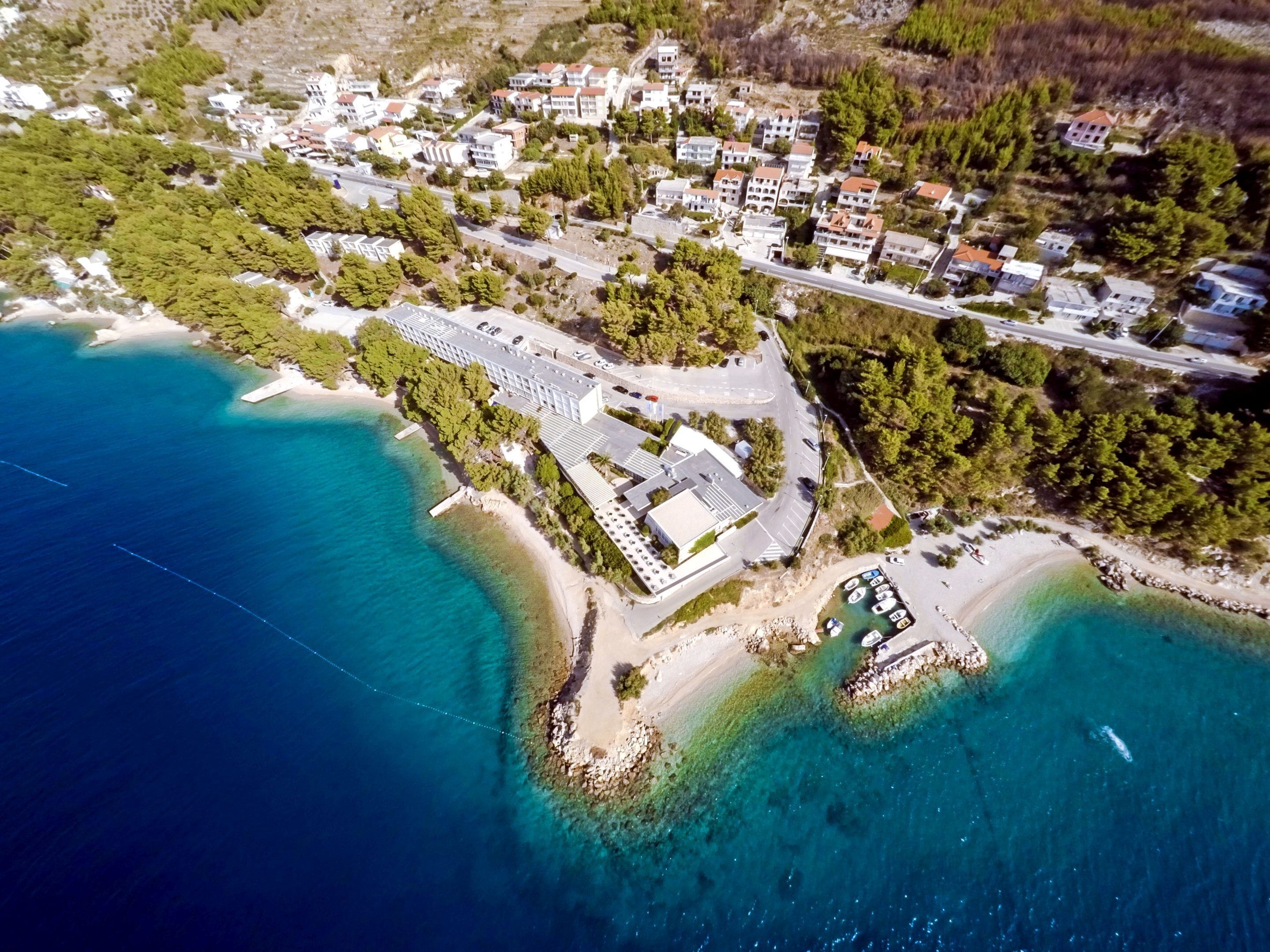 An aerial view of a coastal area with residential buildings, a beach, and a marina.