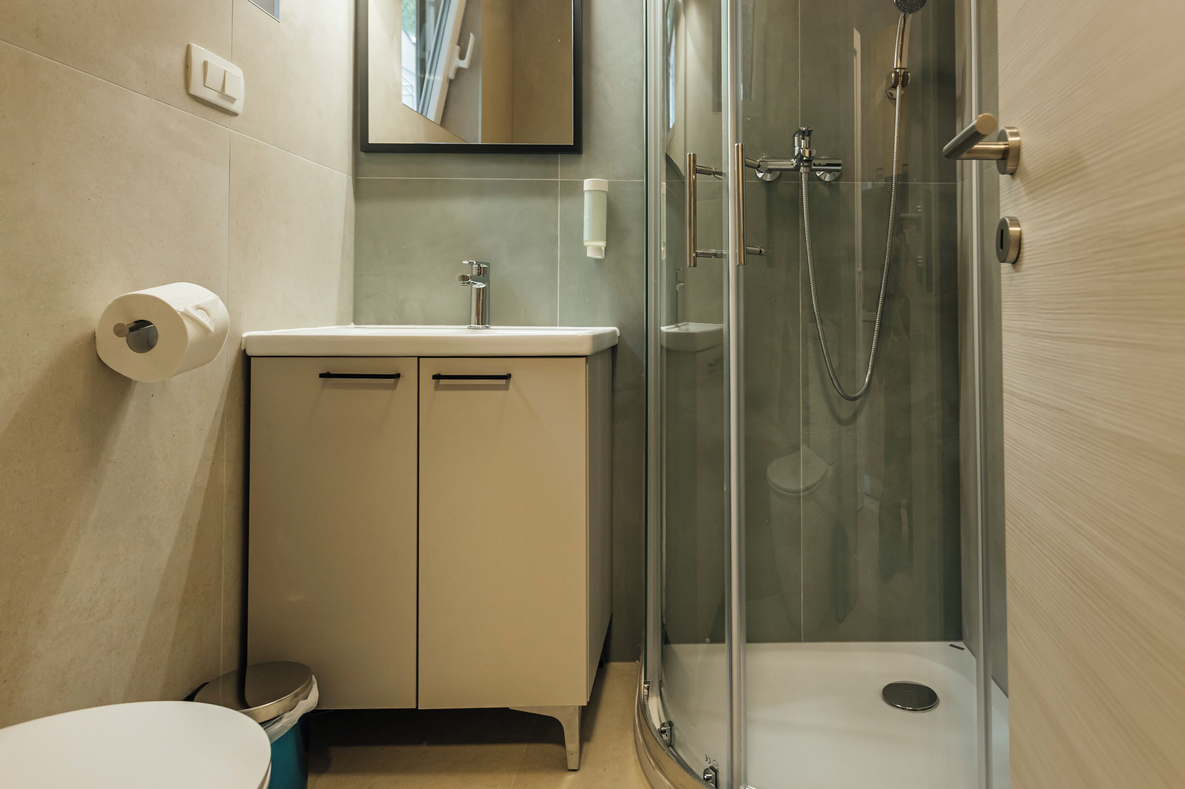 A modern bathroom with a glass-enclosed shower, a white sink, and a toilet.