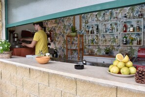 Una zona de bar con mostrador, máquina de café y varias botellas en estanterías.
