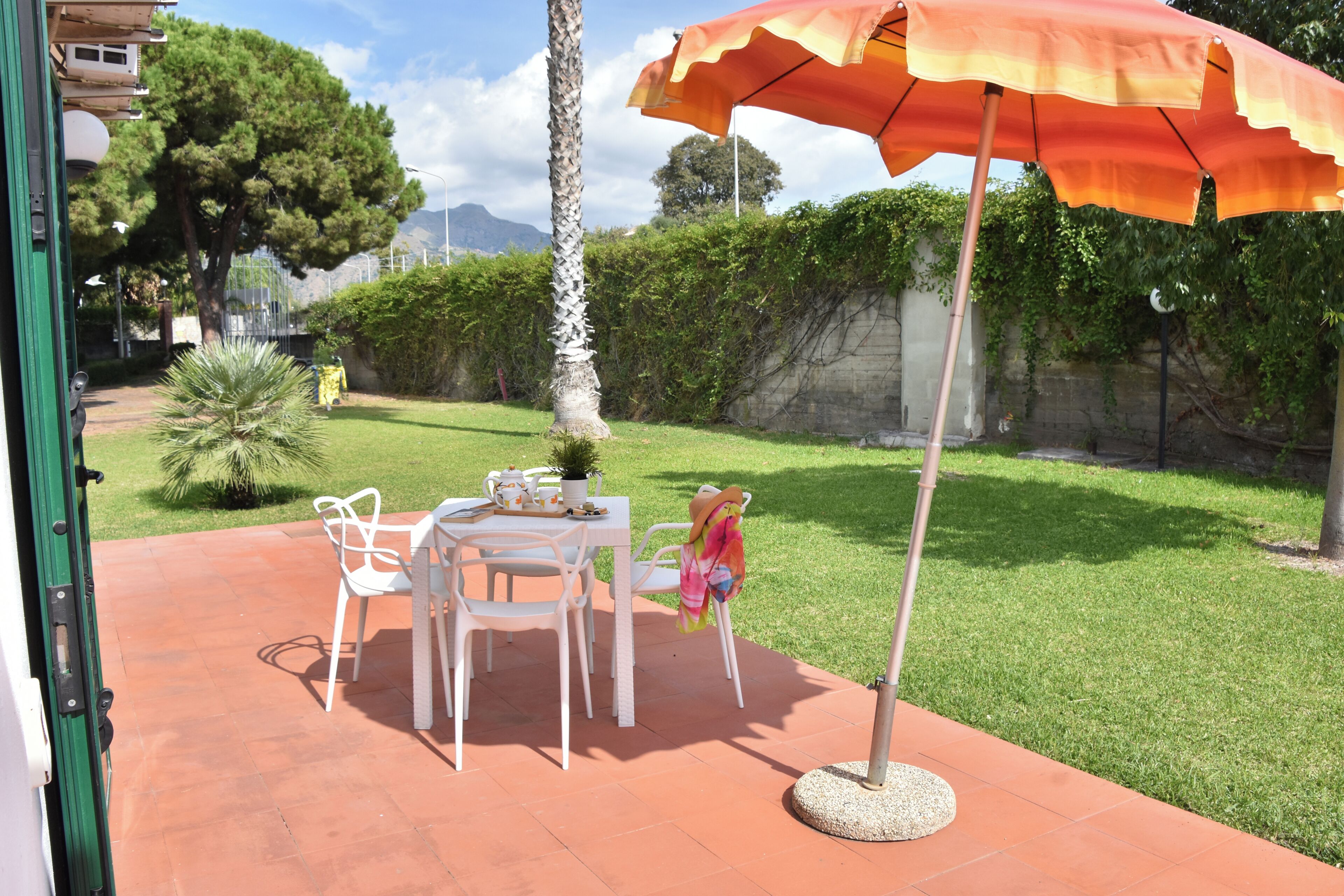 An outdoor patio with a table and chairs, a round table, and a large umbrella.