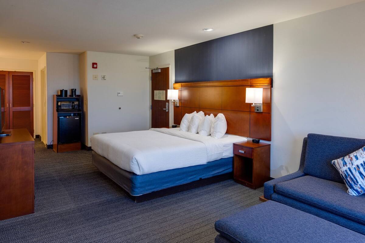 Une chambre d’hôtel avec un grand lit, un canapé, un bureau, un four à micro-ondes et une machine à café.