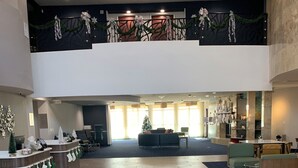 A spacious lobby with a reception desk, seating area, and a staircase leading to an upper level. - Courtyard by Marriott Oklahoma City North/Quail Springs (Oklahoma City)