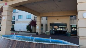 A hotel entrance with a covered walkway, a fountain, and a parking lot. - Courtyard by Marriott Oklahoma City North/Quail Springs (Oklahoma City)