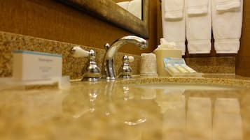 A bathroom sink with a mirror, two faucets, and a soap dispenser.