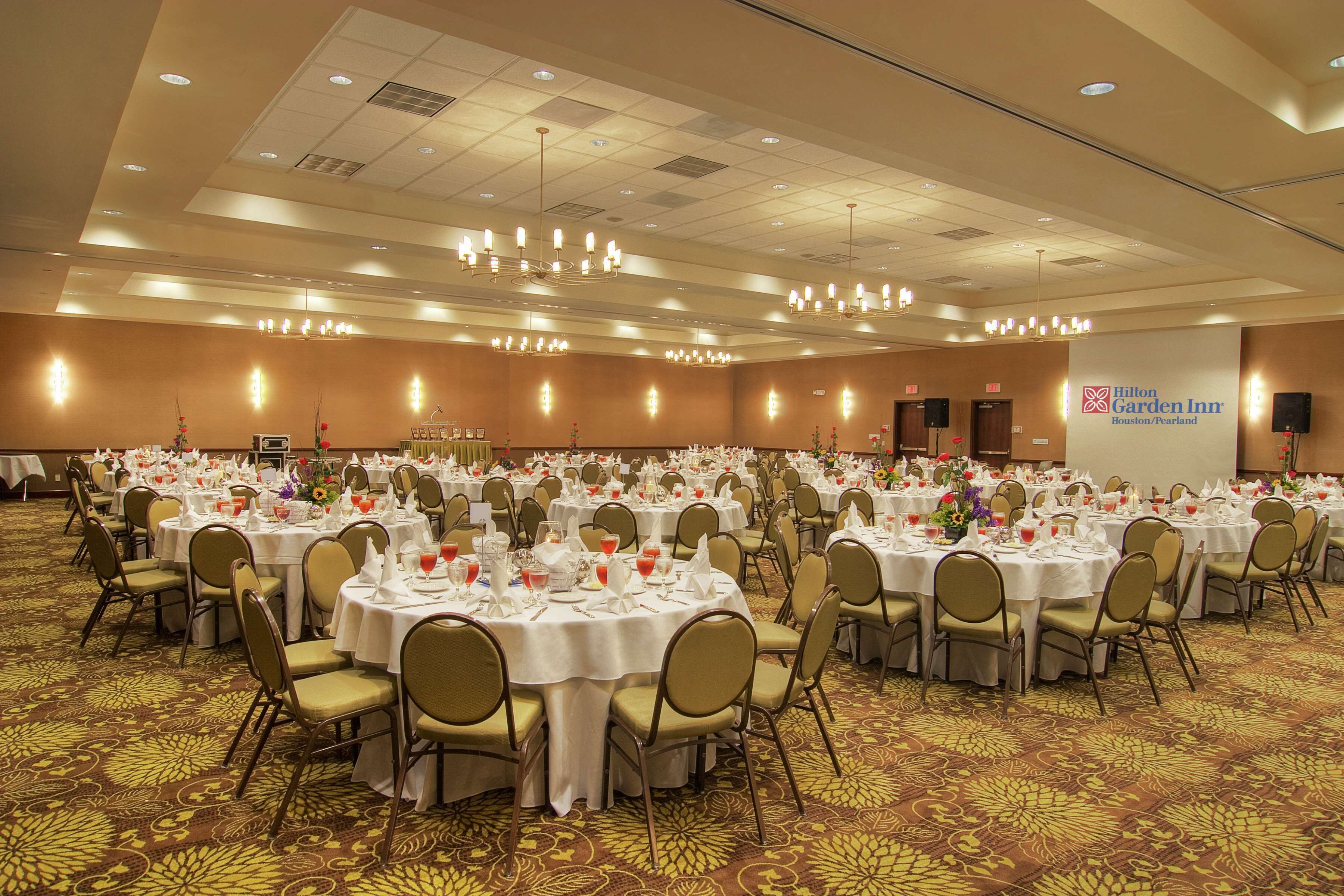 A large banquet hall with round tables set for dining, arranged in rows.