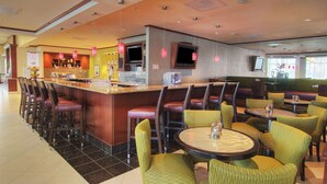 A hotel lobby with a bar area, seating, and a television screen. - Hilton Garden Inn Houston-Pearland (Pearland)