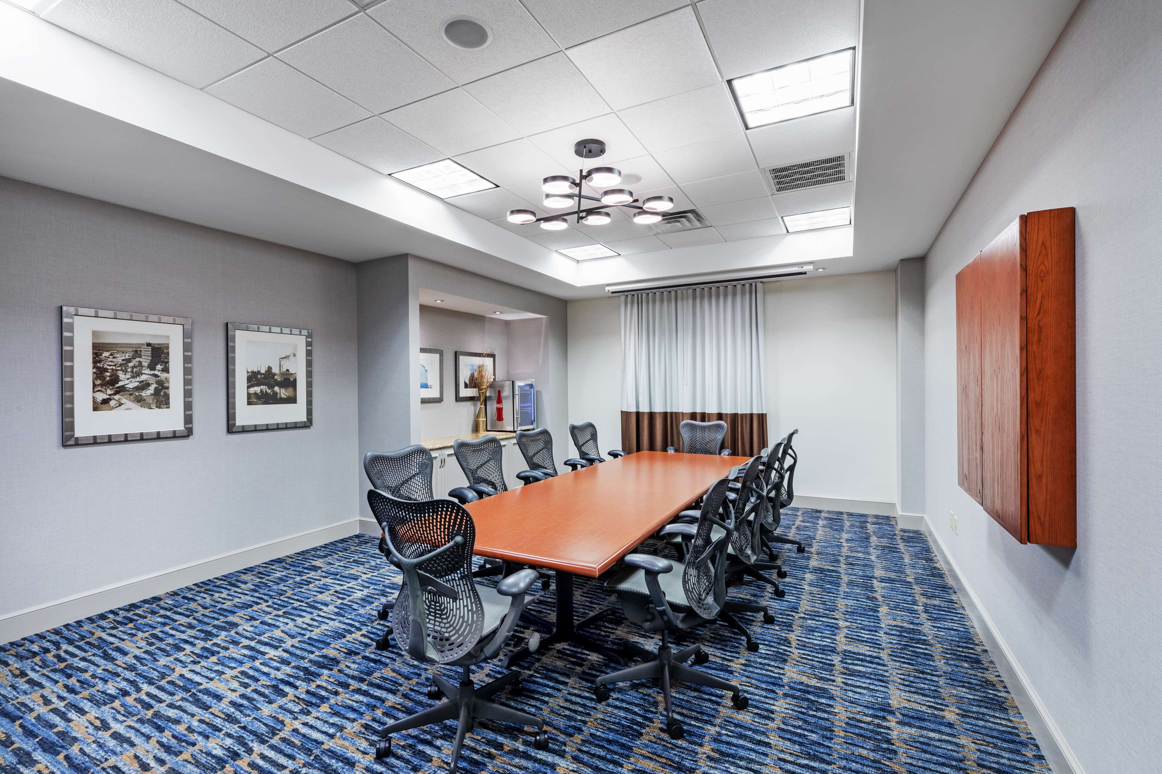 A conference room with a long table, chairs, and a blue patterned carpet.